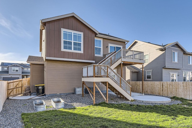 back of property featuring board and batten siding, a lawn, a deck, a fenced backyard, and stairs