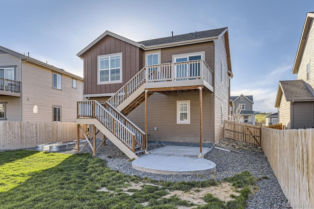 rear view of house featuring stairway, a patio, board and batten siding, and a fenced backyard
