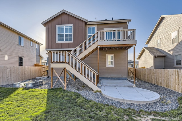 back of property with a wooden deck, a fenced backyard, board and batten siding, a patio area, and stairway
