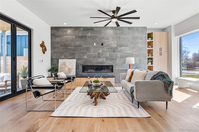 living room featuring ceiling fan, a fireplace, recessed lighting, and wood finished floors