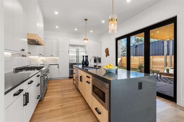 kitchen with white cabinetry, dark countertops, hanging light fixtures, and built in appliances