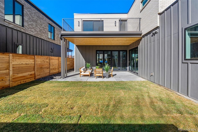 back of property with fence, a patio, board and batten siding, and a yard