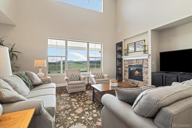 17452 W 83rd Pl, Arvada, CO 80007 - living area featuring wood finished floors, a towering ceiling, a stone fireplace, and baseboards