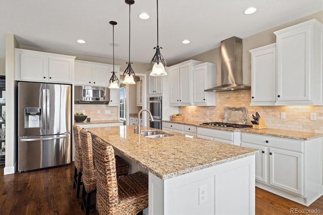 17452 W 83rd Pl, Arvada, CO 80007 - kitchen featuring stainless steel appliances, wall chimney range hood, white cabinets, a center island with sink, and dark wood finished floors