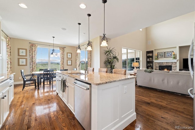 17452 W 83rd Pl, Arvada, CO 80007 - kitchen with dishwasher, a sink, a stone fireplace, white cabinets, and dark wood-style flooring