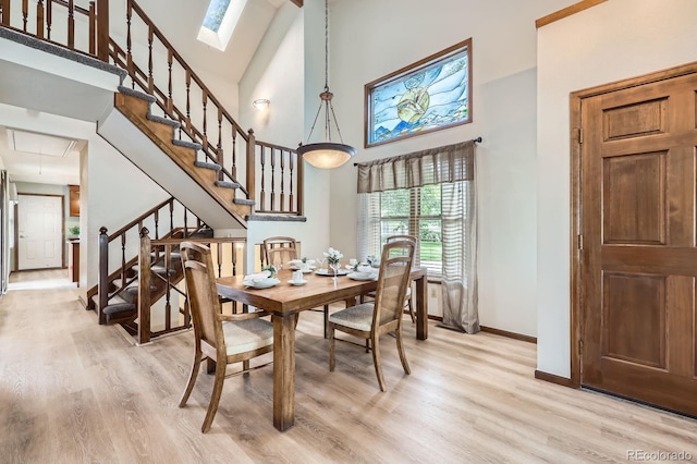 2299 Ranch Dr, Westminster, CO 80234 - dining room featuring a towering ceiling, baseboards, light wood-style floors, stairway, and a skylight