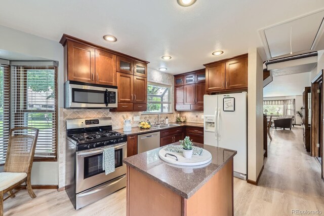 2299 Ranch Dr, Westminster, CO 80234 - kitchen featuring stainless steel appliances, a sink, light wood-style floors, backsplash, and dark stone countertops