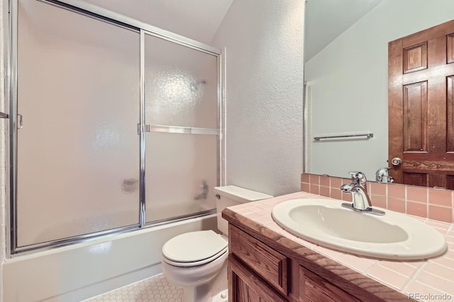 2299 Ranch Dr, Westminster, CO 80234 - full bath with vanity, toilet, combined bath / shower with glass door, a textured wall, and tile patterned floors