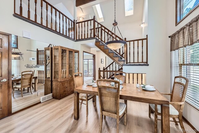 2299 Ranch Dr, Westminster, CO 80234 - dining space featuring a high ceiling, stairs, light wood finished floors, a skylight, and baseboards