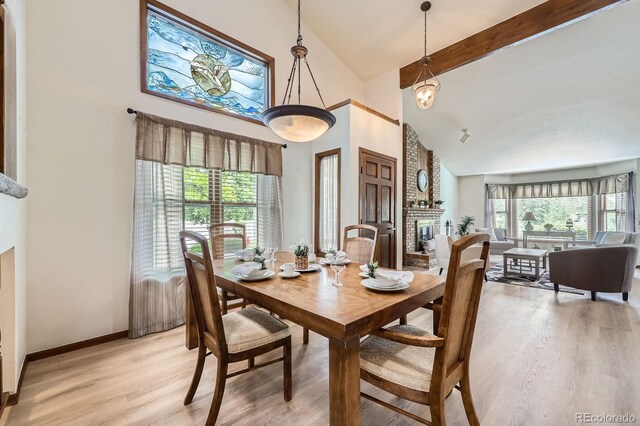 2299 Ranch Dr, Westminster, CO 80234 - dining space featuring high vaulted ceiling, light wood-style flooring, beamed ceiling, a fireplace, and baseboards