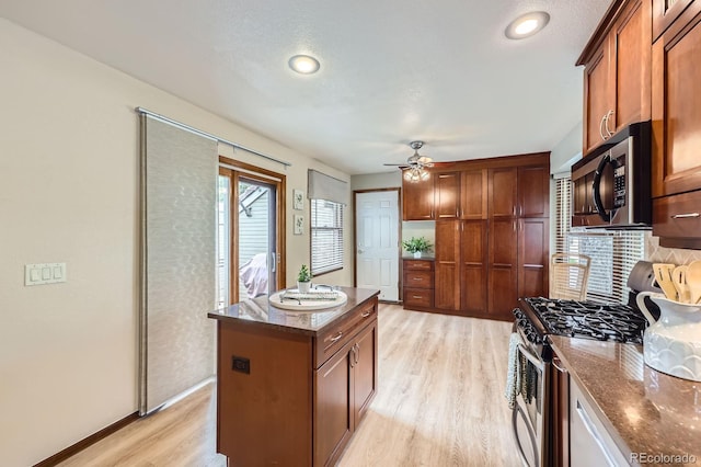 2299 Ranch Dr, Westminster, CO 80234 - kitchen with appliances with stainless steel finishes, light wood finished floors, dark stone countertops, a ceiling fan, and brown cabinets