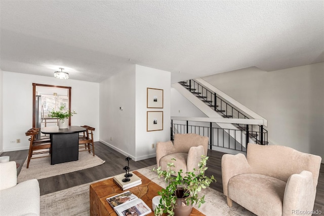 living area featuring stairway, a textured ceiling, baseboards, and wood finished floors