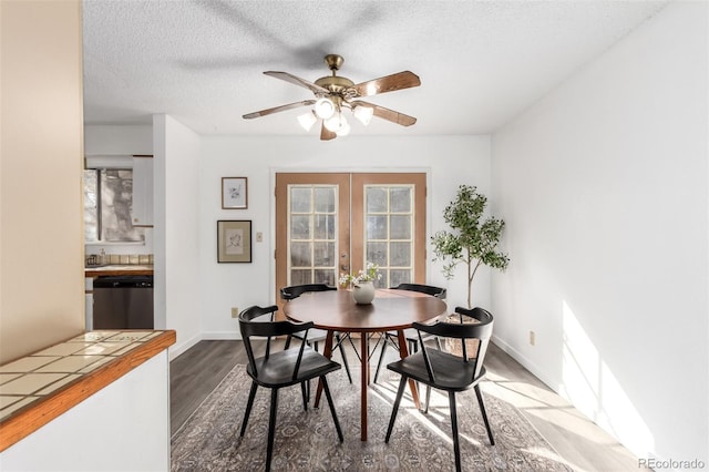 dining room with a textured ceiling, french doors, dark wood-style flooring, and baseboards