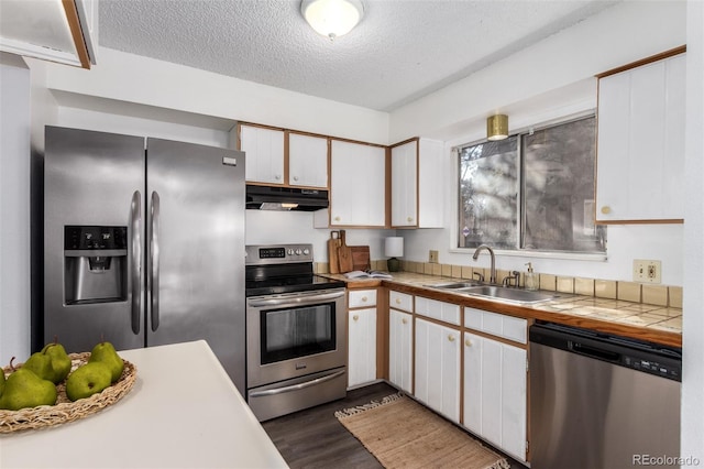 kitchen with dark wood finished floors, appliances with stainless steel finishes, a textured ceiling, under cabinet range hood, and a sink