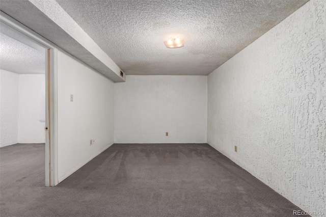 empty room featuring carpet flooring, a textured wall, and a textured ceiling