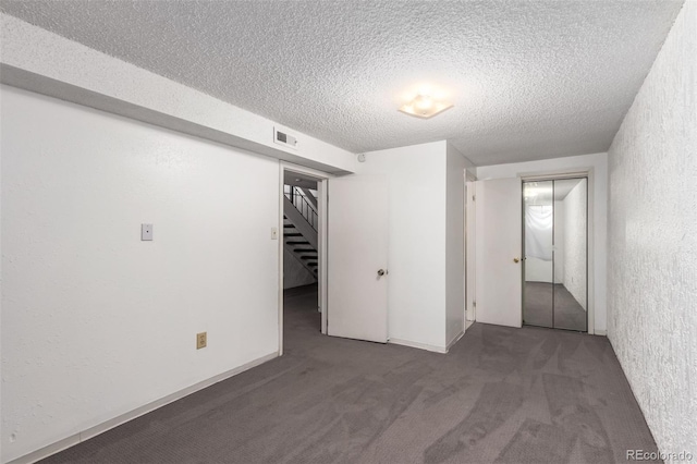 unfurnished bedroom featuring carpet floors, visible vents, a textured ceiling, and a textured wall