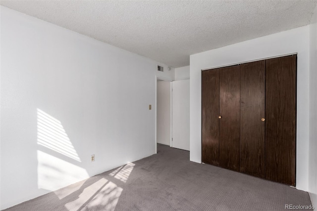 unfurnished bedroom with carpet floors, a textured ceiling, visible vents, and a closet