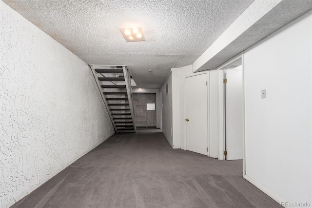 corridor featuring a textured ceiling, a textured wall, stairway, and carpet floors