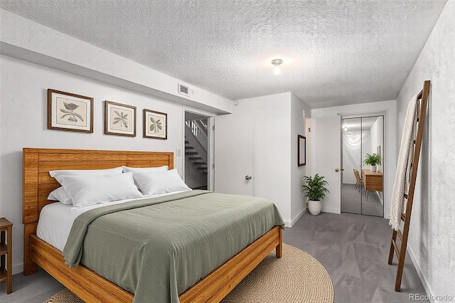 bedroom with carpet floors, a closet, visible vents, a textured ceiling, and baseboards