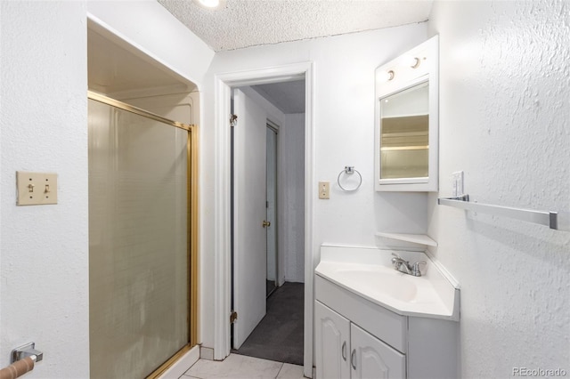 bathroom featuring a textured ceiling, tile patterned flooring, a shower stall, and vanity