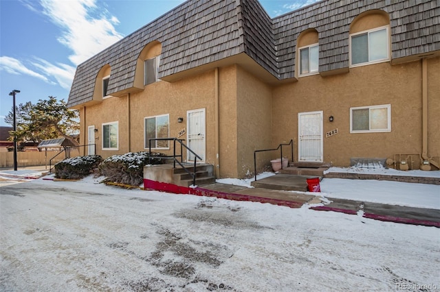 exterior space with stucco siding and mansard roof