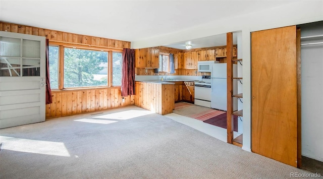 28958 Buffalo Park Rd, Evergreen, CO 80439 - kitchen featuring white appliances, brown cabinets, a peninsula, wood walls, and light colored carpet