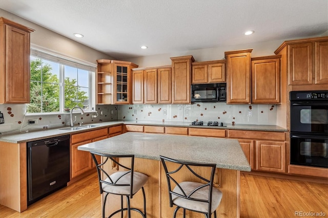 26155 E Euclid Dr, Aurora, CO 80016 - kitchen with black appliances, light wood-type flooring, brown cabinets, a breakfast bar, and backsplash