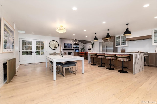 1 Club Ln, Littleton, CO 80123 - kitchen featuring appliances with stainless steel finishes, french doors, a breakfast bar area, light wood-style flooring, and glass insert cabinets