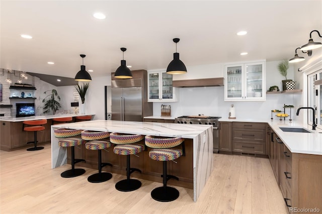 1 Club Ln, Littleton, CO 80123 - kitchen featuring premium appliances, light wood-style flooring, glass insert cabinets, a breakfast bar area, and recessed lighting