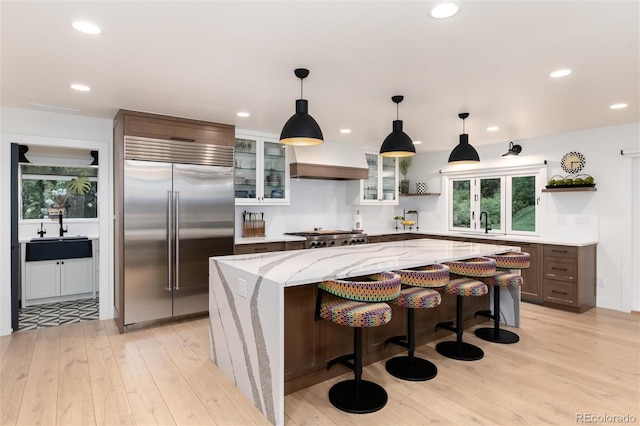 1 Club Ln, Littleton, CO 80123 - kitchen with stainless steel built in refrigerator, open shelves, recessed lighting, light wood-style floors, and glass insert cabinets