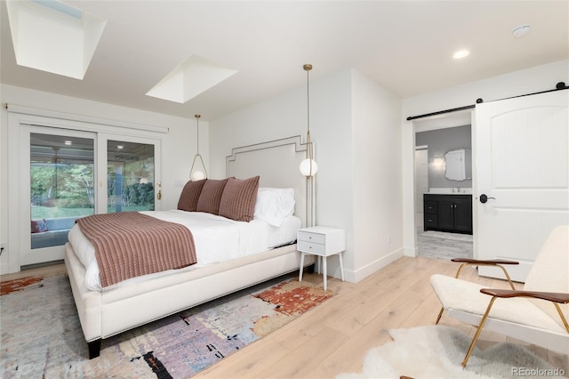 1 Club Ln, Littleton, CO 80123 - bedroom featuring a skylight, light wood-type flooring, a barn door, recessed lighting, and connected bathroom