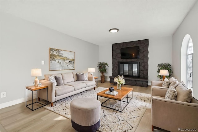 living room featuring a stone fireplace and light hardwood / wood-style floors