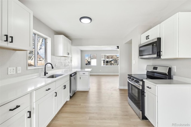 kitchen featuring sink, white cabinetry, light wood-type flooring, ceiling fan, and stainless steel appliances