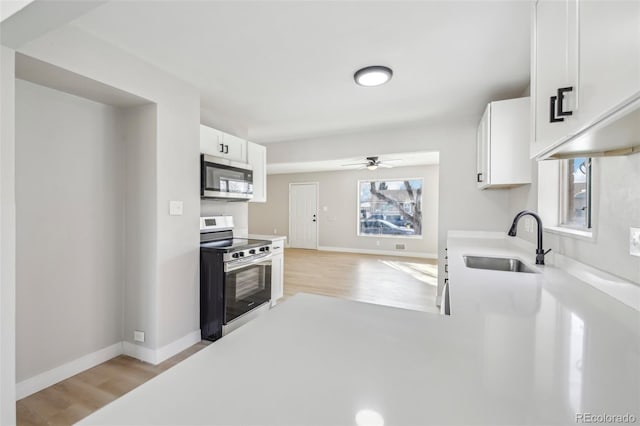 kitchen featuring white cabinetry, sink, ceiling fan, stainless steel appliances, and light wood-type flooring