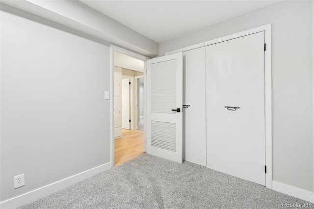 unfurnished bedroom featuring light colored carpet and a closet