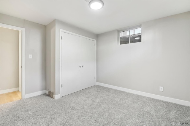 unfurnished bedroom featuring light colored carpet and a closet