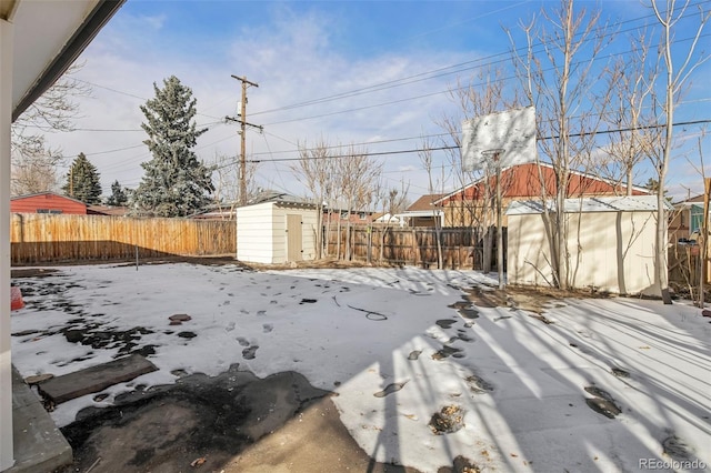 snowy yard featuring a shed