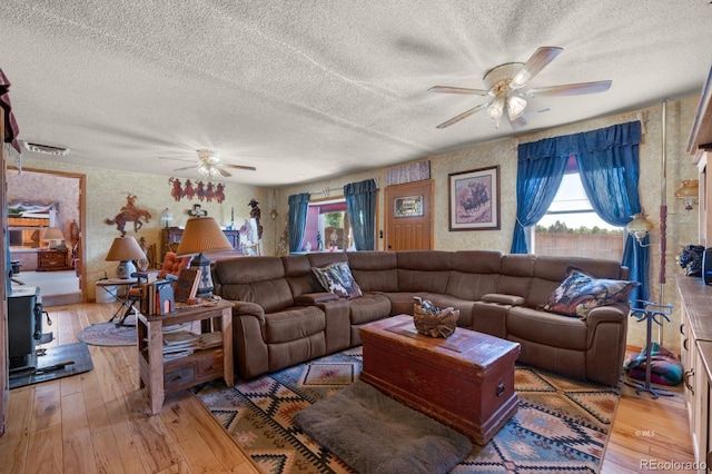 living room with a textured ceiling, ceiling fan, and hardwood / wood-style floors