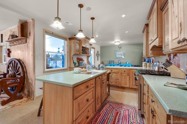 kitchen featuring stainless steel stove, a breakfast bar, a kitchen island with sink, and light tile patterned floors