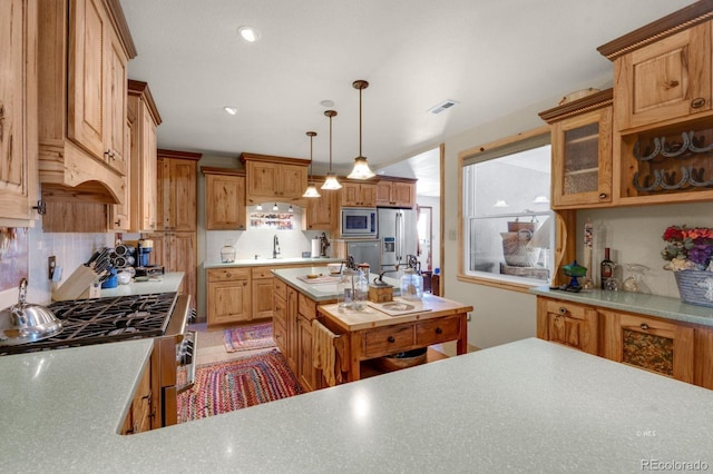 kitchen with sink, decorative light fixtures, backsplash, and stainless steel appliances