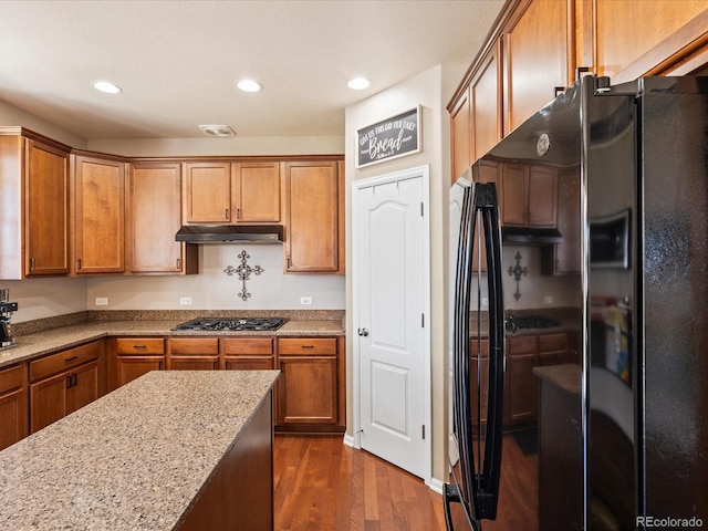 2853 Black Canyon Way, Castle Rock, CO 80109 - kitchen featuring freestanding refrigerator, under cabinet range hood, light stone countertops, dark wood finished floors, and stainless steel gas stovetop