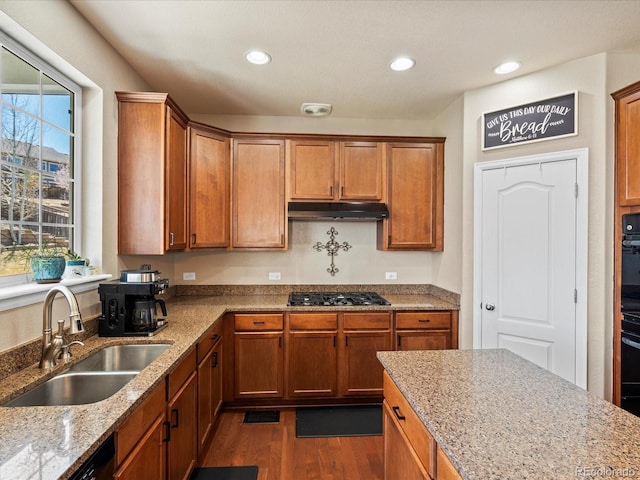 2853 Black Canyon Way, Castle Rock, CO 80109 - kitchen featuring dark wood finished floors, stainless steel gas stovetop, light stone counters, under cabinet range hood, and a sink
