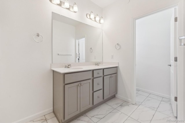 full bath with marble finish floor, a sink, baseboards, and double vanity