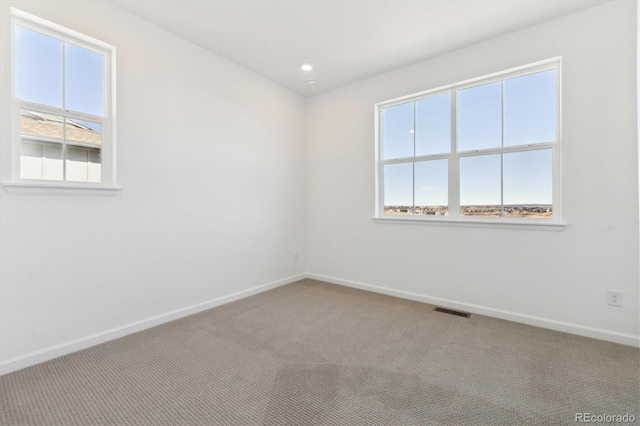 carpeted spare room featuring baseboards, visible vents, and recessed lighting