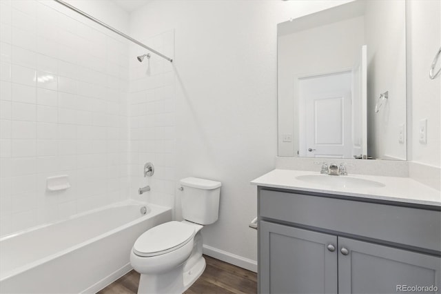 bathroom featuring baseboards, toilet, wood finished floors, tub / shower combination, and vanity