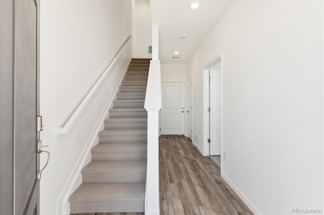 stairs featuring recessed lighting, visible vents, baseboards, and wood finished floors