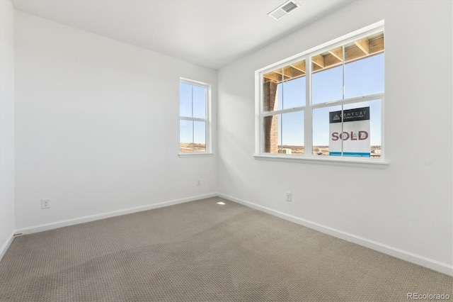 spare room with carpet, visible vents, and baseboards