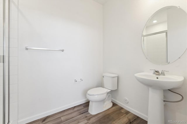 full bath with toilet, a sink, wood finished floors, tiled shower, and baseboards