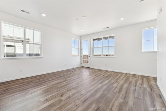 spare room with wood finished floors, visible vents, and baseboards