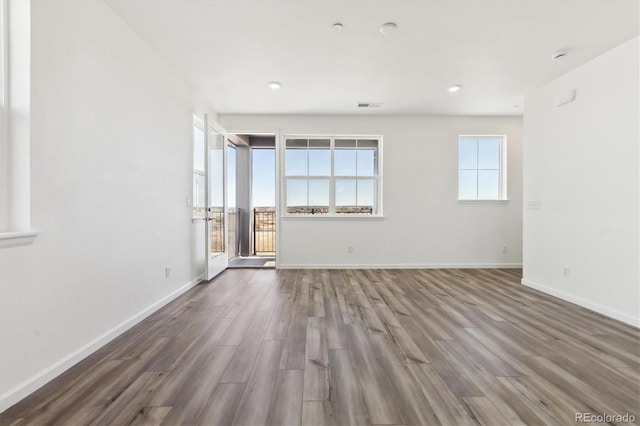 unfurnished room with visible vents, baseboards, and wood finished floors